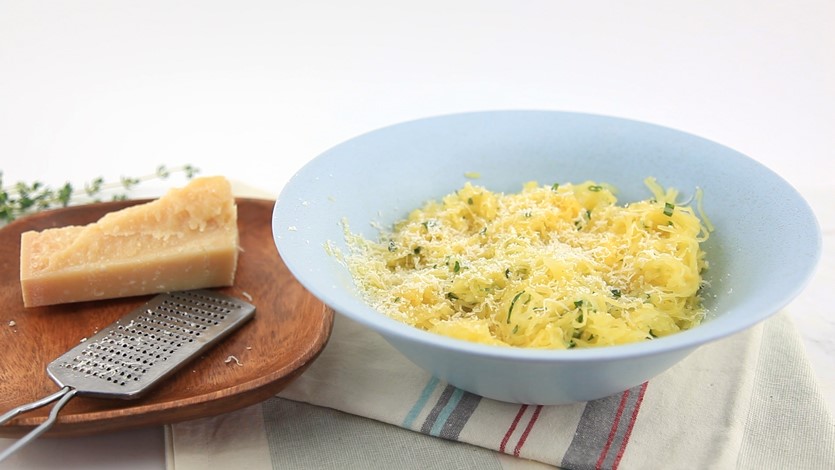 Spaghetti squash in a white bowl with herb butter and parm cheese