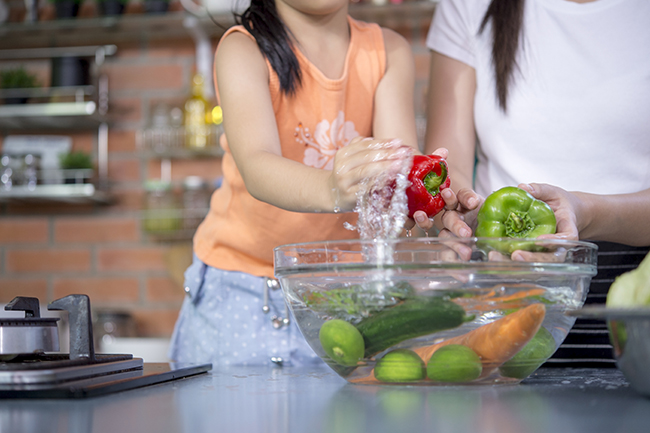 Mains laver les légumes frais paprika rouge, vert, jaune, dans un bol en verre.