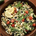 A bowl of lemon orzo pasta on a wooden table