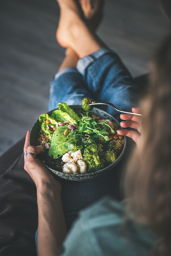Woman holding a salad with avocado and green sauce